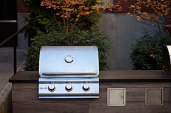 A silver grill with four burners is on a wooden table.